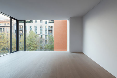 A spacious, minimalistic room with large windows allows ample natural light to fill the space. Outside, a vibrant urban landscape features trees and buildings, creating a serene atmosphere.の素材
