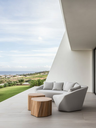 A sleek outdoor lounge area features contemporary furniture, offering a relaxing view of the lush landscape and distant hills under a clear sky.の素材
