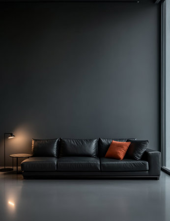 A sleek black leather sofa is positioned against a dark wall, featuring an orange accent pillow. A minimalist lamp illuminates the area, creating a cozy atmosphere in a modern interior.の素材