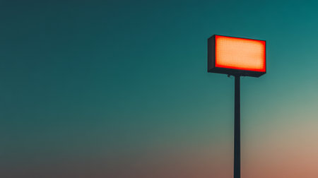 A tall, rectangular sign stands alone in the fading light of dusk, illuminated from within. The sky transitions from bright blue to deep orange as the day ends, creating a calm atmosphere.の素材