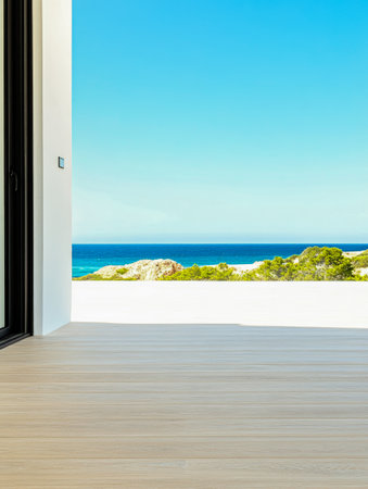 A spacious modern room features large windows opening to a stunning coastal view of the ocean and blue sky. The light wood floor adds warmth to the serene atmosphere.の素材