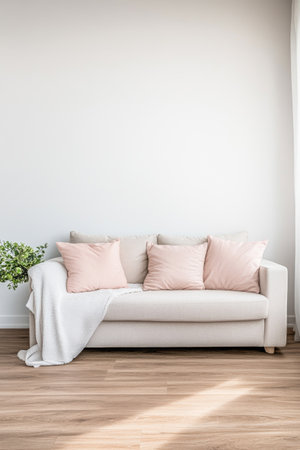A light-colored sofa adorned with soft pastel cushions sits against a plain wall. A cozy blanket drapes over one side, while a small potted plant adds a touch of greenery to the minimalist space.の素材