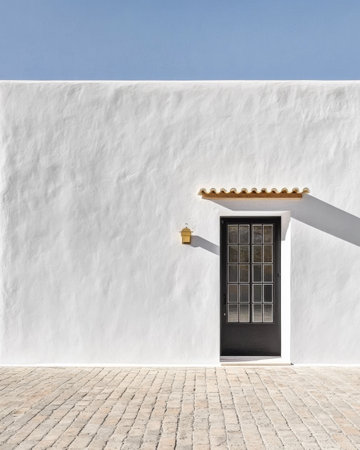 This setting features a clean white wall with a stylish black door and a warm lantern, creating a tranquil and inviting atmosphere in bright daylight.の素材