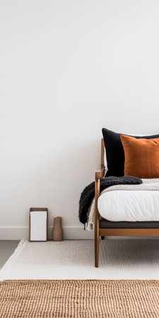 A serene bedroom features a stylish bed adorned with warm-toned pillows and a textured blanket, complemented by neutral decor and natural light filtering through the space.の素材