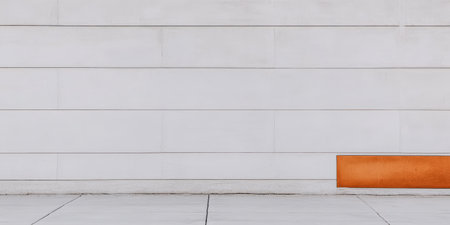 A textured white wall serves as the backdrop for a striking orange bench. The scene captures a peaceful urban environment during midday, highlighting design and color contrast.の素材