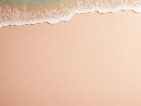 Soft waves roll gently onto a light pink sandy beach, creating a tranquil atmosphere during the golden hour. The calm water reflects hues of blue and gold in the fading sunlight.の素材