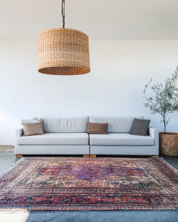 Stylish light grey sofa with decorative pillows sits on an intricate patterned rug in a spacious well-lit living area. A woven pendant light hangs above adding warmth to the decor.の素材