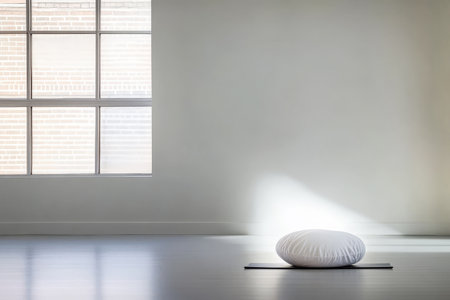 A serene corner features a round cushion placed on a mat illuminated by soft sunlight coming through a large window creating a peaceful atmosphere ideal for meditation and mindfulness.の素材