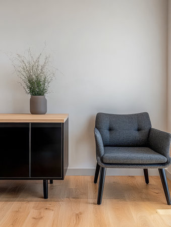 A contemporary living area displays a gray upholstered chair beside a sleek wooden sideboard. A simple vase with green foliage adds a touch of nature to the minimalist decor.の素材