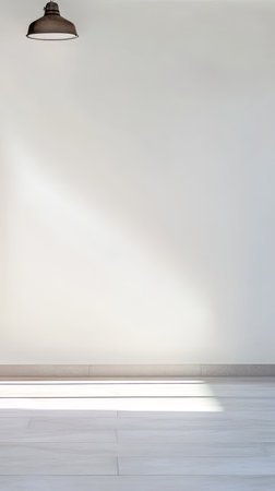 A well-lit minimalist interior showcases a clean white wall and floor with soft shadows. A pendant light hangs from the ceiling adding a modern touch to the simple space.の素材
