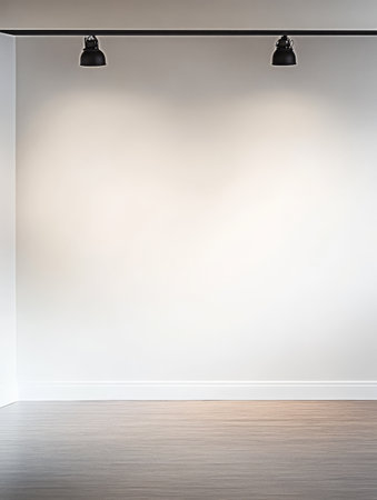 An empty room featuring a bright wall with two black ceiling lights illuminating the space. The wooden floor adds warmth to the minimalistic setting ideal for various uses.の素材