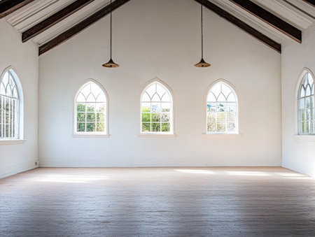A large airy room features three arched windows allowing natural light to flood in. The minimalist design highlights the wooden beam ceiling and pale wooden floor.の素材