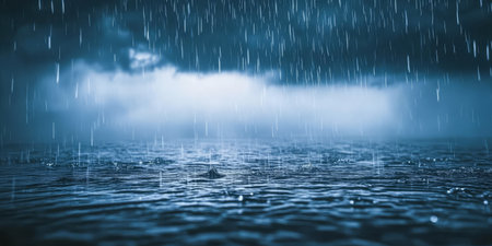 Heavy rain cascades onto the calm ocean surface at twilight. Dark clouds loom above creating a moody atmosphere as ripples form on the water from falling droplets.の素材