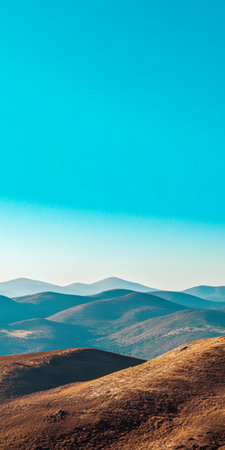 Wide expanse of undulating hills stretches across the landscape illuminated by the midday sun. A vivid blue sky casts a serene atmosphere over the natural scenery.の素材