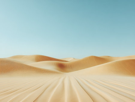 Soft golden sand stretches across rolling dunes in a tranquil desert. The clear blue sky contrasts beautifully with the warm tones of the landscape creating a peaceful atmosphere.の素材