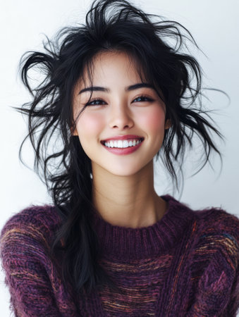A young woman displays a bright smile with her hair playfully styled. She wears a soft cozy sweater creating a warm and inviting atmosphere. The light background enhances her joyful expression.の素材
