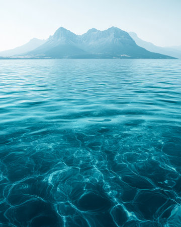 Calm turquoise water reflects majestic mountains under a clear sky. Early morning light creates a serene atmosphere highlighting the beauty of nature in this stunning landscape.の素材