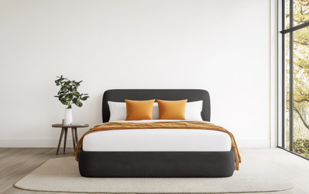 A stylish bedroom features a comfortable bed adorned with orange cushions and a textured throw. Natural light floods the space highlighting a sleek side table and a green plant.の素材