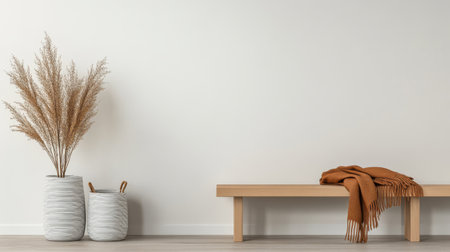 A cozy space features two decorative vases with dried plants beside a simple wooden bench. A warm blanket is draped over the bench complementing the minimalist aesthetic.の素材