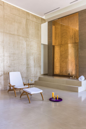 A serene spa interior showcases a minimalist design featuring a wooden lounge chair soothing candles and a calm ambiance. The setting invites relaxation and tranquility.の素材