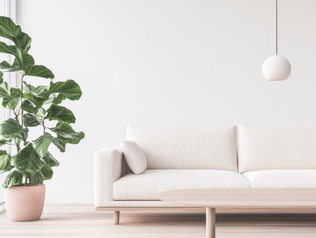 A spacious modern living room features a white textured sofa with a small cushion. It is complemented by a large green indoor plant in a pink pot and a simple pendant light hanging above.の素材