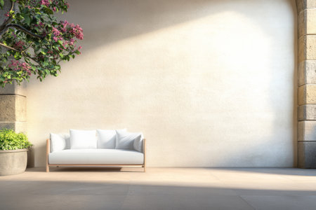 A bright and inviting courtyard features a white sofa placed against a textured wall. Lush greenery and blooming flowers enhance the tranquil atmosphere in this open space.の素材