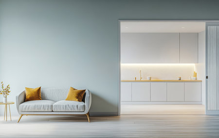 A stylish living room features a gray sofa with gold accent pillows. The open kitchen area has soft lighting and clean lines creating a warm inviting environment perfect for relaxation.の素材