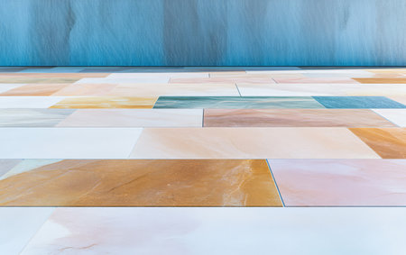 The tiled floor features an array of colorful patterns with hues of beige peach and blue. Soft daylight illuminates the tiles highlighting their distinct textures and shapes.の素材