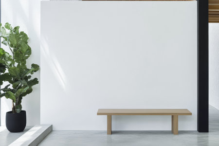 A spacious modern interior features a simple wooden bench against a white wall. A lush green plant adds a touch of nature. Bright natural light streams in enhancing the serene atmosphere.の素材