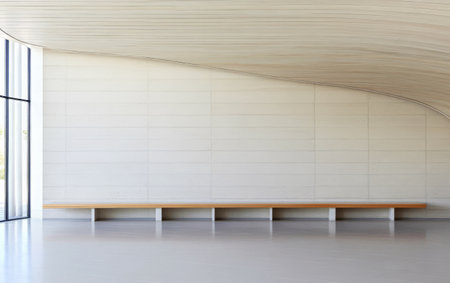 A spacious minimalist interior features a long wooden bench against a smooth curved wall. Natural light floods the area through large glass windows enhancing the tranquil atmosphere.の素材