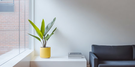 A cozy living area featuring a dark sofa next to a white table. A vibrant green plant in a yellow pot thrives in natural light from a large window enhancing the ambiance of the space.の素材