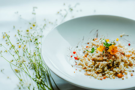 A meticulously arranged rice dish features herbs and edible flowers atop a bed of grains. Delicate blossoms and greens add a touch of elegance creating a fresh culinary delight.の素材