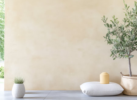 Soft light fills an outdoor area with a plain wall a potted olive tree a textured cushion and a minimalist candle. This tranquil setup creates a serene atmosphere for relaxation.の素材