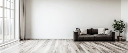 A spacious living room features a simple gray sofa adorned with cushions large windows allowing natural light and a potted plant enhancing the minimal decor.の素材