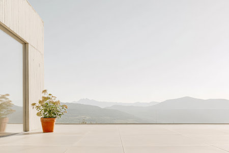 A minimalist outdoor area showcases a potted plant next to a large glass window overlooking a peaceful mountain backdrop under a clear sky. This tranquil setting highlights nature and design.の素材