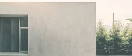 A sleek minimalist building stands against a backdrop of lush greenery under a clear sky. The exterior features smooth lines and a neutral palette reflecting a contemporary aesthetic.の素材