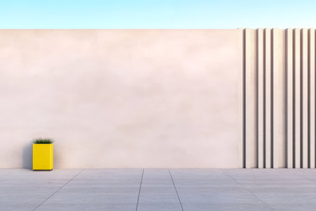 A minimalist outdoor area showcases a pale wall with vertical grooves and a vibrant yellow planter holding grass. The clear blue sky creates a serene atmosphere emphasizing simplicity.の素材
