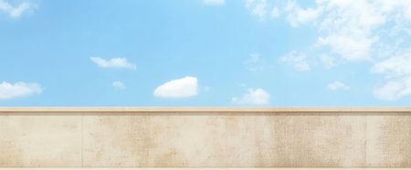 A vast blue sky dotted with fluffy white clouds stretches overhead, while a textured beige wall sits prominently below, illuminated by the bright sunlight of midday.の素材