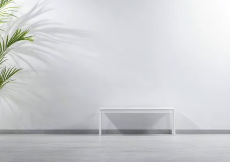 A minimalist style interior features a sleek white bench positioned against a plain wall. A lush green indoor plant adds life and warmth to the serene and bright environment.の素材
