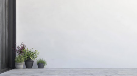Potted plants in various sizes and shapes are positioned neatly against a blank wall on a patio. The setting has a minimalist design with a modern aesthetic, enhancing the greenery.の素材