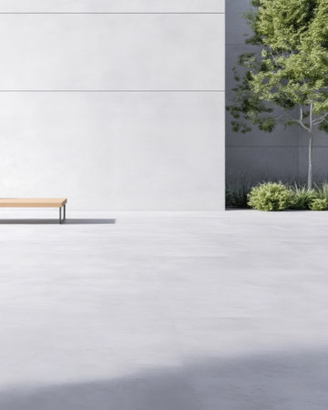 A minimalist bench sits alone on a smooth concrete surface surrounded by greenery, creating a tranquil atmosphere in an urban space, inviting relaxation and reflection.の素材