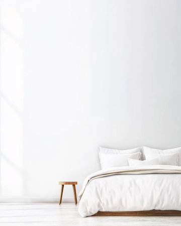 A spacious bedroom showcases a large bed with soft white bedding and pillows accompanied by a simple wooden nightstand. Bright sunlight filters through a window enhancing the serene atmosphere.の素材
