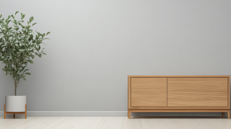 A modern living room features a light wood cabinet with two drawers placed against a pale wall. An indoor plant in a white pot adds a touch of greenery to the simple decor.の素材