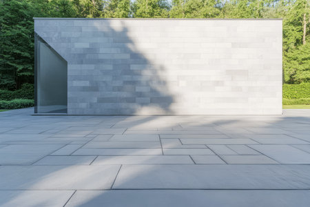 A sleek minimalist building integrates with its natural surroundings. Soft shadows play on the stone surface highlighting the contemporary design amidst lush greenery.の素材