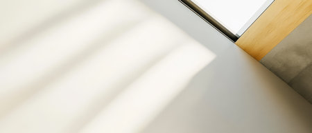 Soft sunlight casts gentle shadows across a minimalist indoor wall creating a peaceful atmosphere in a contemporary setting. The light enhances the neutral colors of the room.の素材
