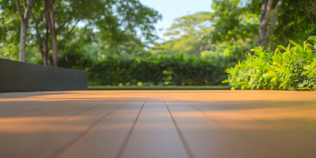 Warm sunlight creates long shadows on a smooth wooden deck framed by vibrant greenery. A serene garden ambiance invites relaxation and reflection on a clear day.の素材