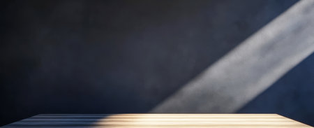 Sunlight casts a warm glow on a simple wooden table set against a dark textured background. The contrasting elements create a serene minimalist atmosphere.の素材