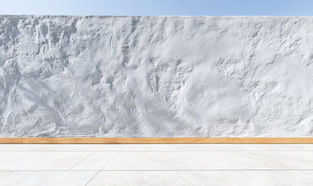 A bright space featuring a textured white wall with a smooth finish. A wooden baseboard runs along the bottom contrasting with the walls surface while natural light illuminates the area.の素材