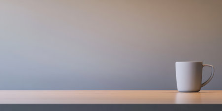 A clean white cup sits quietly on a smooth wooden table with a subtle gradient background. The soft lighting creates a calm atmosphere suggesting a moment of relaxation.の素材