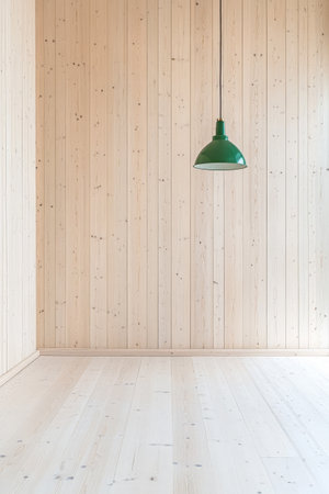 A spacious interior showcases light wooden walls and flooring illuminated by a simple green pendant light hanging from the ceiling. The overall design emphasizes clean lines and minimalism.の素材